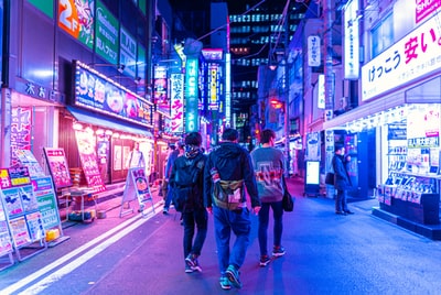 男人穿蓝色牛仔裤走在街头在夜间
